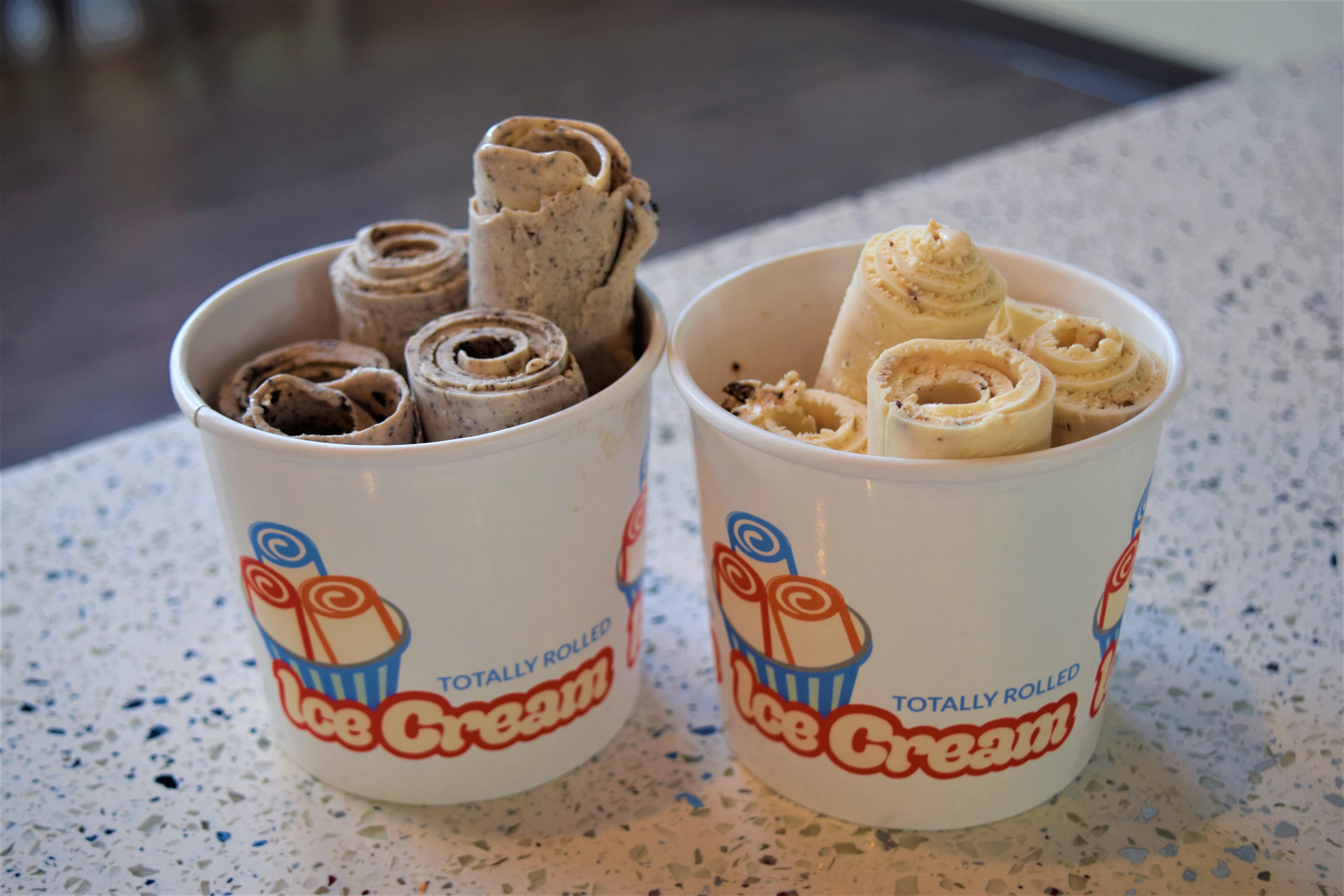 Freshly rolled ice cream served in a cup with beautiful presentation and toppings